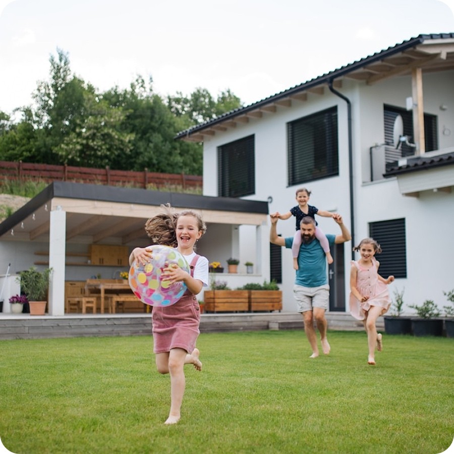 A family playing together in the backyard of their home at sunset