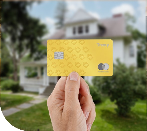 A hand holding a Trovy HELOC credit card in front of a home